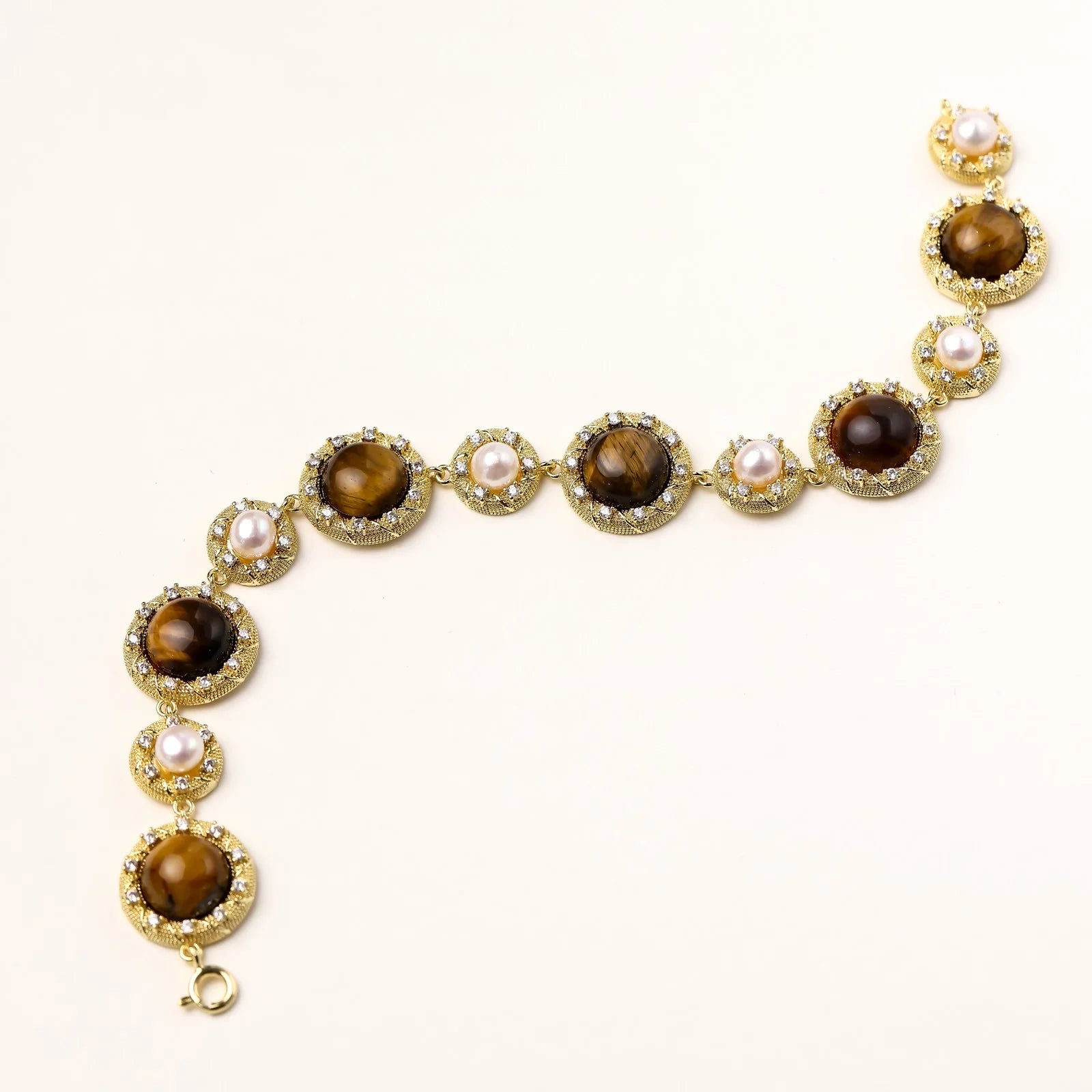 Gold-plated link bracelet with alternating brown tiger's eye stones and white freshwater pearls in ornate bezels.