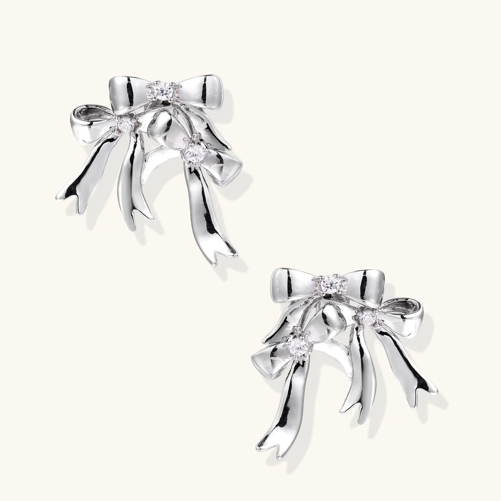 Sculptural bow earrings in polished white gold plate with sparkling zirconia stones and flowing ribbon details