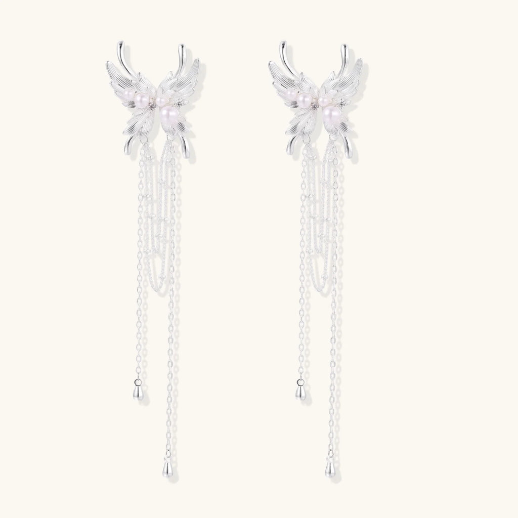 Elegant chandelier earrings with phoenix wing design, white pearls, and cascading silver chains on cream background