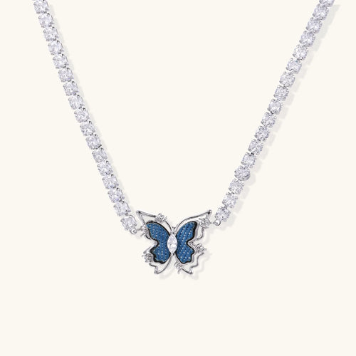 White gold plated tennis necklace with blue denim butterfly pendant and clear zirconia stones on cream background