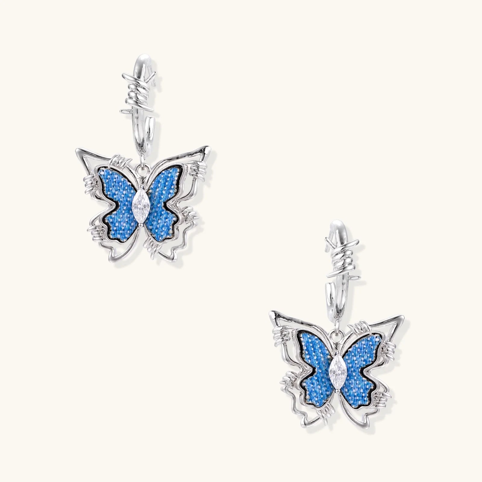 Silver hoop earrings with blue denim butterfly charms outlined in barbed wire design and central zirconia stone