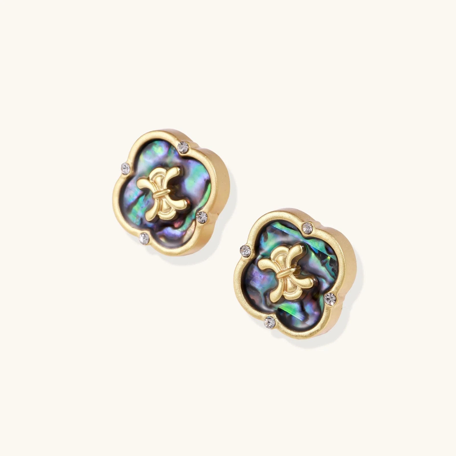 Gold quatrefoil stud earrings with iridescent abalone shell inlay and fleur-de-lis center, accented by four crystals