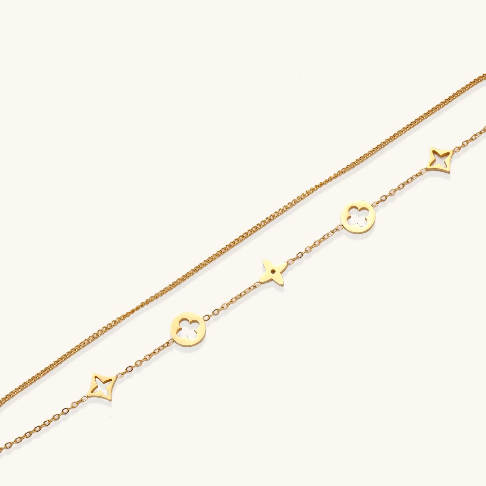 Double-layer gold-plated bracelet with quatrefoil and star charms on cream background, 18K gold finish.