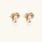 Gold-plated flower stud earrings with textured petals and centered freshwater pearl on beige background