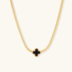 Dainty 18K gold-plated herringbone chain necklace with black enamel quatrefoil clover pendant on white background