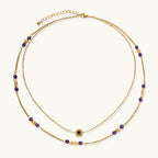 Two layered gold-tone necklaces with purple stone beads and star pendant against cream background.