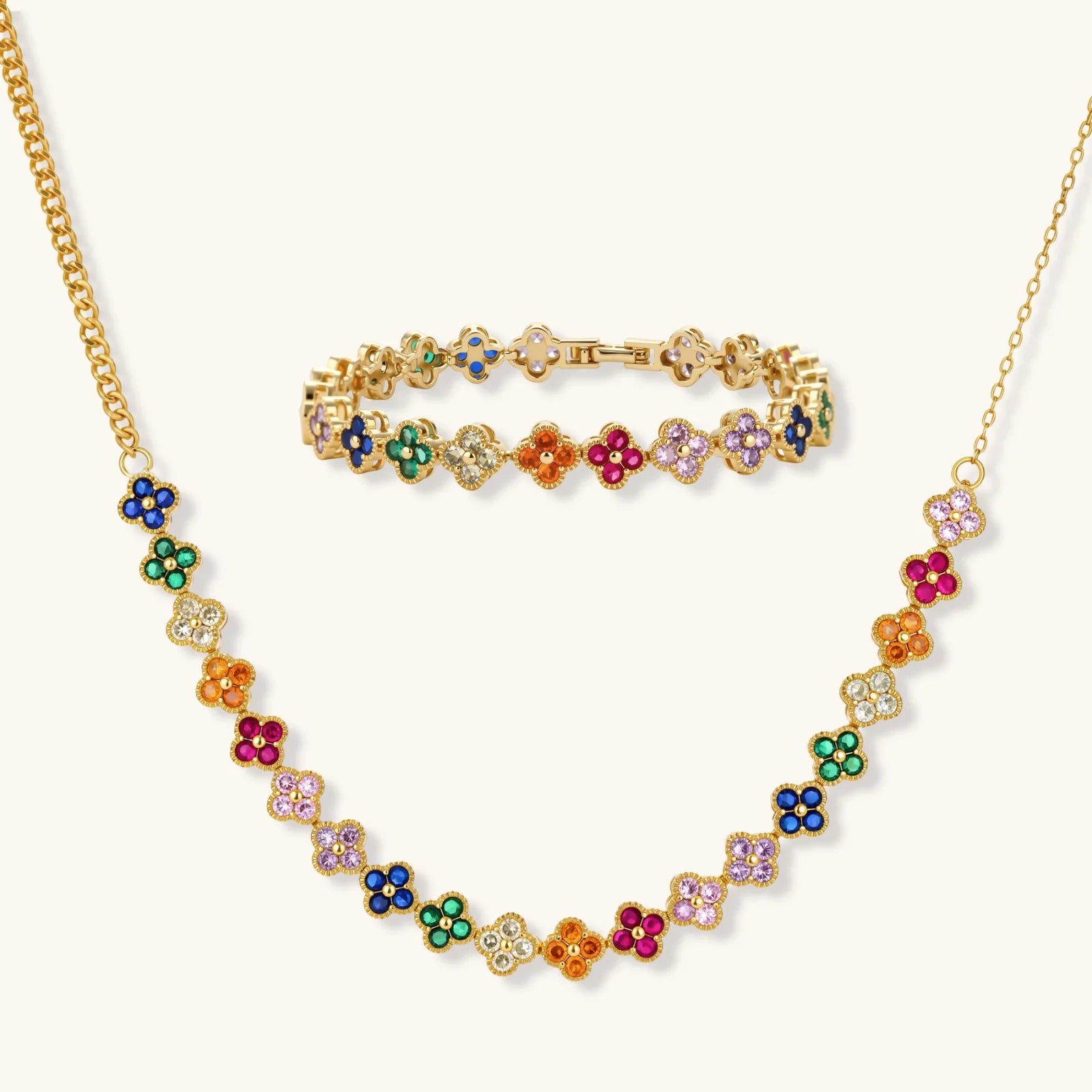 Colorful four-leaf clover jewelry set with rainbow cubic zirconia stones in gold-plated setting on white background