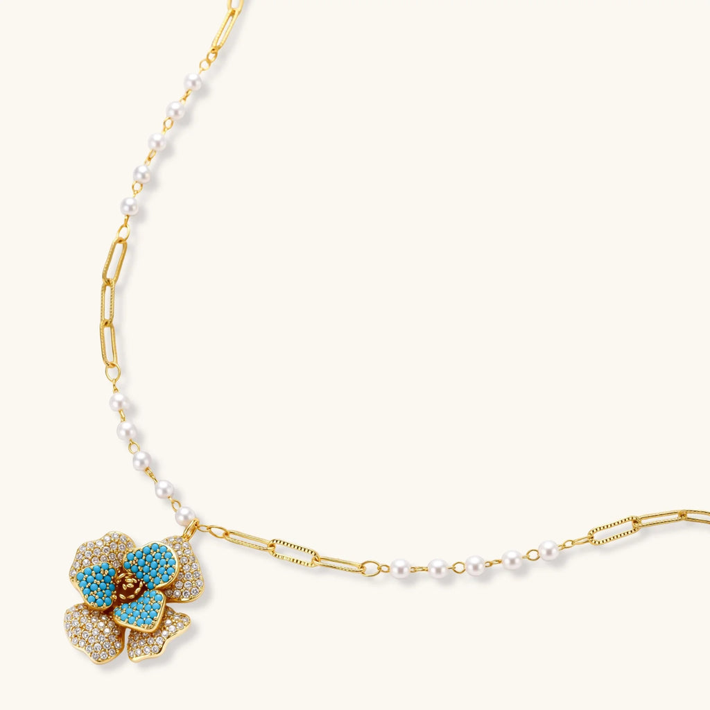 14K gold-plated floral jewelry set with blue cubic zirconia centers and pearl chain details on white background.