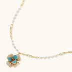 14K gold-plated floral jewelry set with blue cubic zirconia centers and pearl chain details on white background.