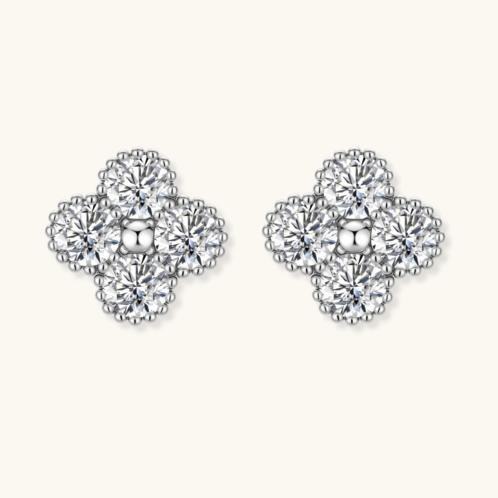 Dainty sterling silver quatrefoil stud earrings with four brilliant moissanite stones and center accent on white background.