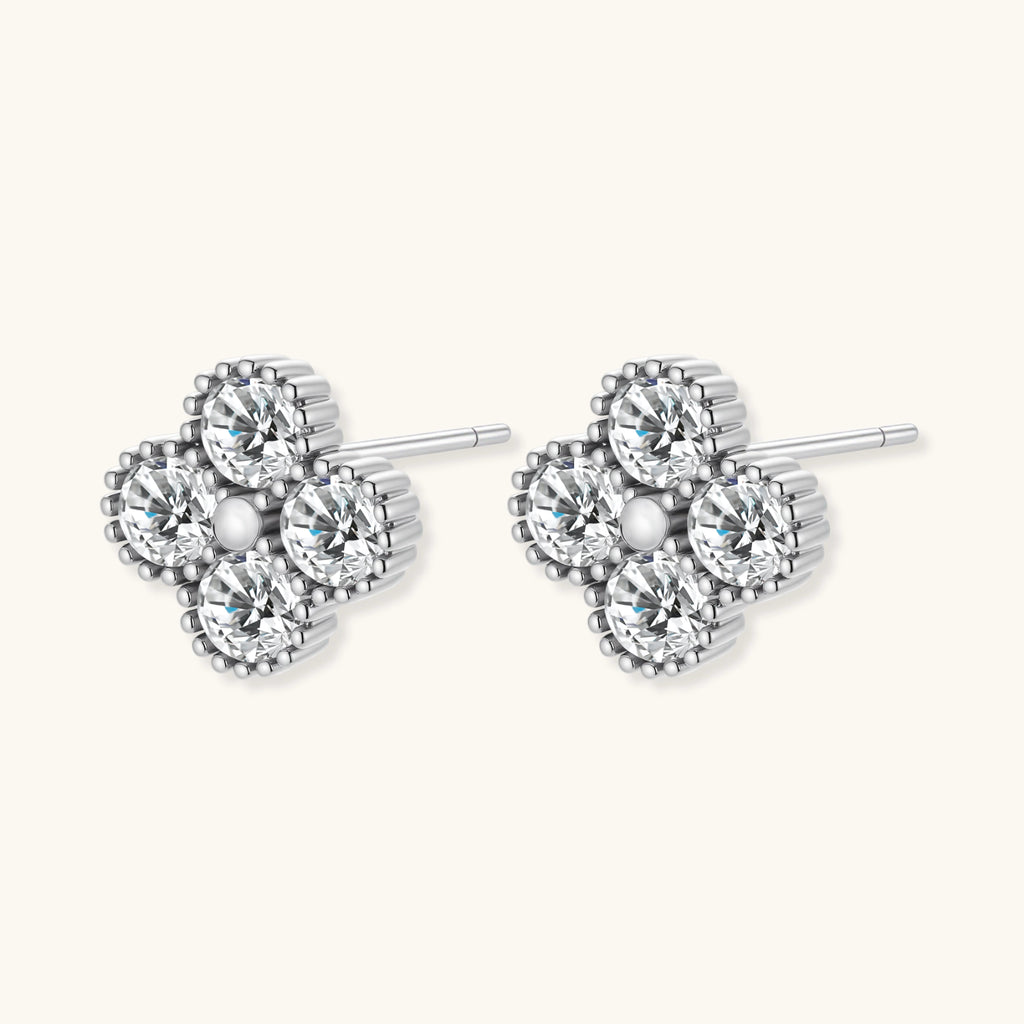 Dainty sterling silver quatrefoil stud earrings with four brilliant moissanite stones and center accent on white background.
