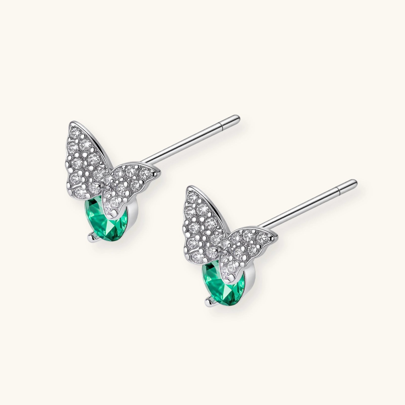 Sterling silver butterfly stud earrings with crystal wings and mint green center stones on cream background.