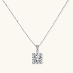 Square moissanite pendant with halo setting on delicate sterling silver chain against white background.