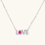Sterling silver LOVE necklace with pink moissanite stone replacing the O, featuring crystal-set letters on delicate chain.