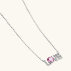 Sterling silver LOVE necklace with pink moissanite stone replacing the O, featuring crystal-set letters on delicate chain.