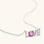 Sterling silver LOVE necklace with pink moissanite stone replacing the O, featuring crystal-set letters on delicate chain.