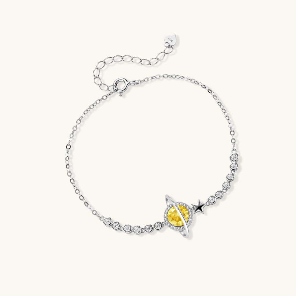 Sterling silver bracelet with yellow moissanite centerpiece in oval setting, crystal chain, and star charm on white background.