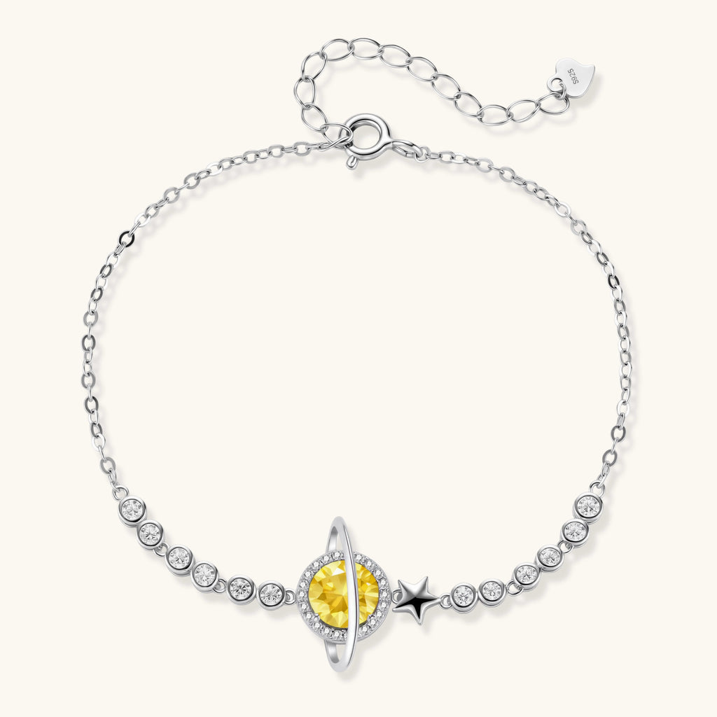 Sterling silver bracelet with yellow moissanite centerpiece in oval setting, crystal chain, and star charm on white background.