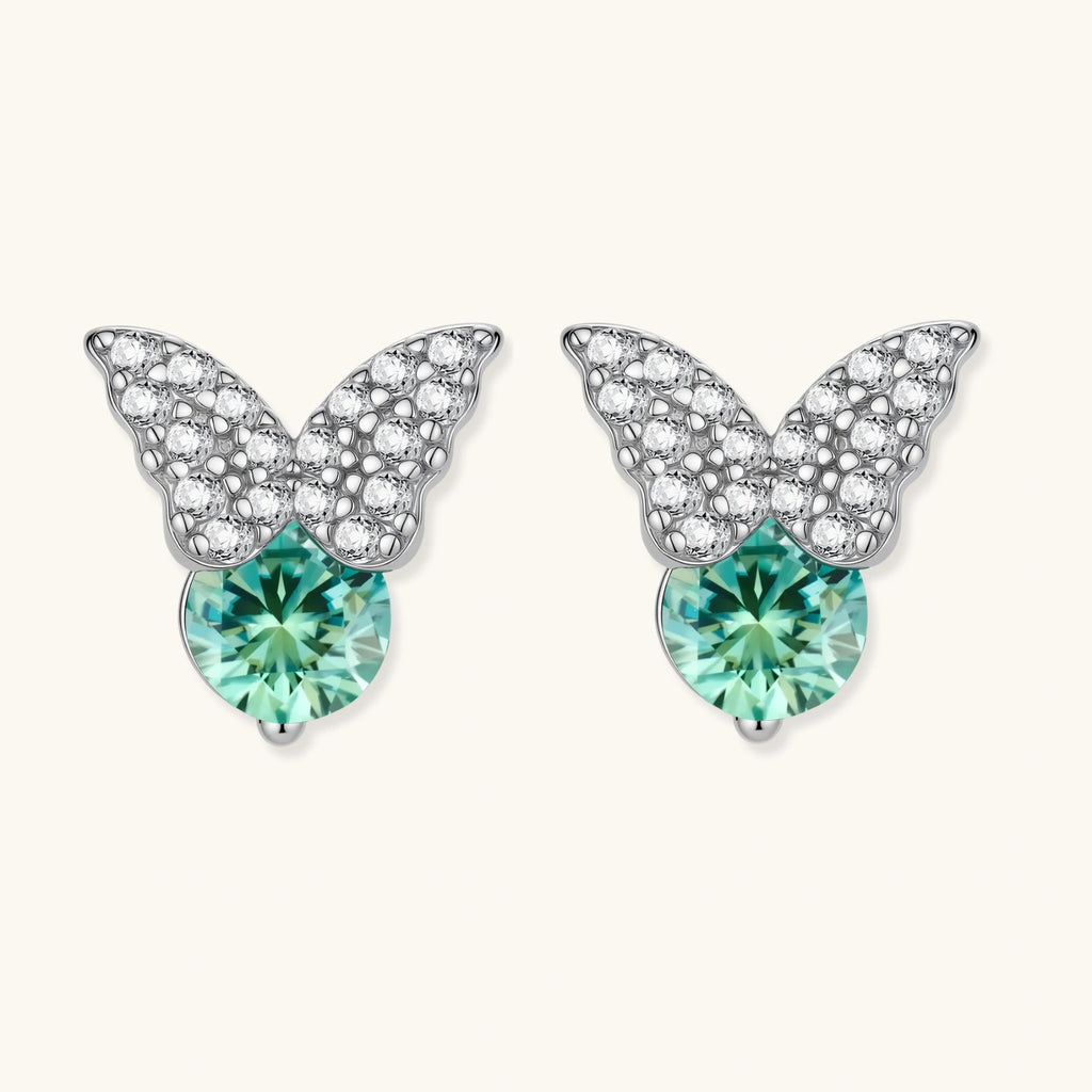 Sterling silver butterfly stud earrings with crystal wings and mint green center stones on cream background.