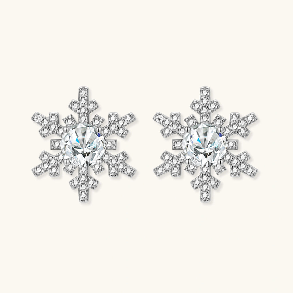 Sterling silver snowflake stud earrings with brilliant moissanite centers and intricate geometric patterns on cream background