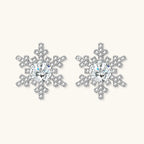 Sterling silver snowflake stud earrings with brilliant moissanite centers and intricate geometric patterns on cream background