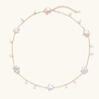 Gold vermeil chain with iridescent star-shaped baroque pearls and small round freshwater pearl drops on cream background.