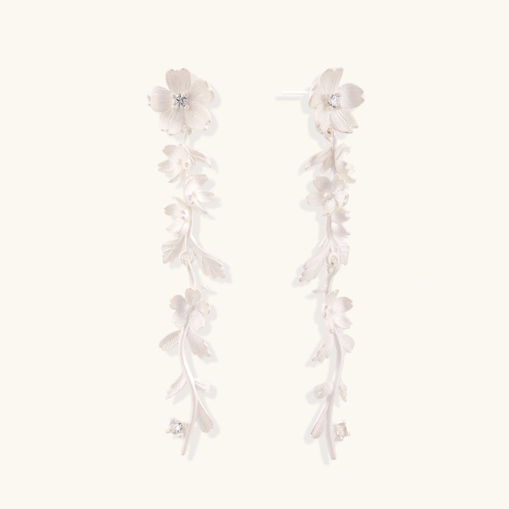 Long sterling silver drop earrings with delicate floral vine design and crystal accents on white background