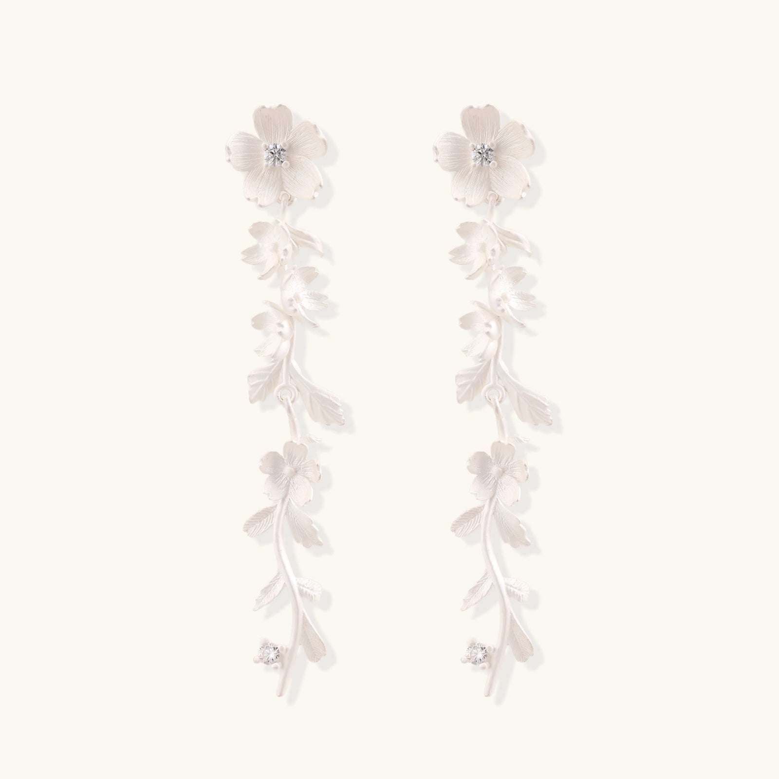 Long sterling silver drop earrings with delicate floral vine design and crystal accents on white background