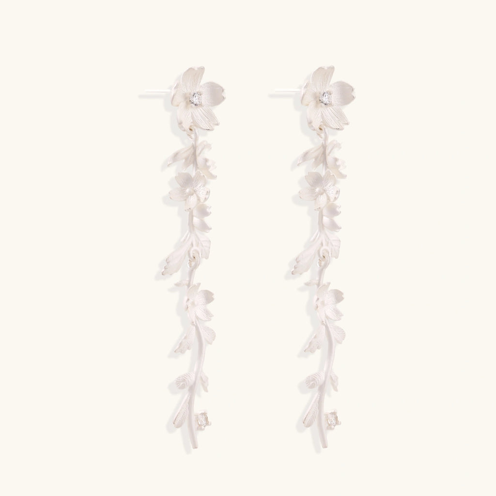 Long sterling silver drop earrings with delicate floral vine design and crystal accents on white background