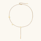 Gold Y-shaped necklace with L-O-V-E letter charms and vertical bar pendant on delicate chain against cream background