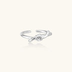 Delicate rhodium-plated silver ring with elegant knot design on cream background, adjustable band style