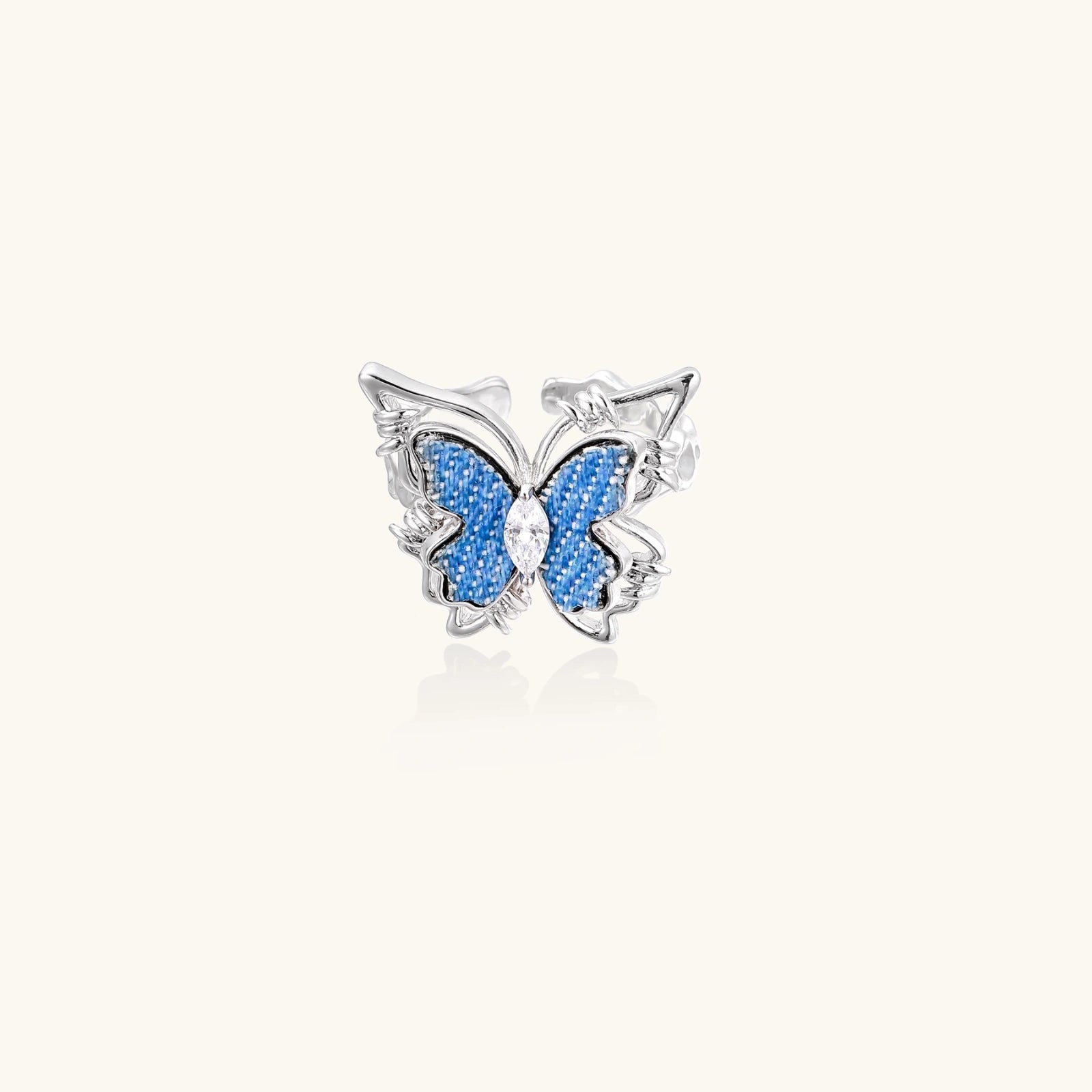 Silver-toned ring with blue denim butterfly wings, marquise zirconia center, and ornate scrollwork band on white background